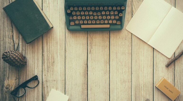 Picture of typewriter sitting in between a book and a journal.