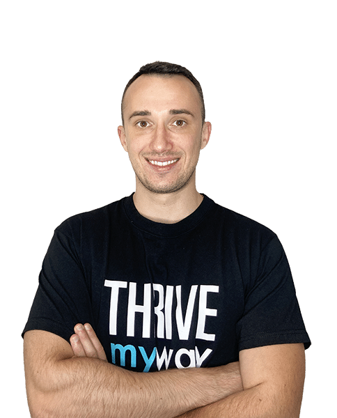 Picture of a man wearing a black shirt with the words Thrive My Way on it. Thrive is in all caps and white lettering. My and way are both in lowercase. My is blue, way is white. The man has his arms crossed underneath the logo.